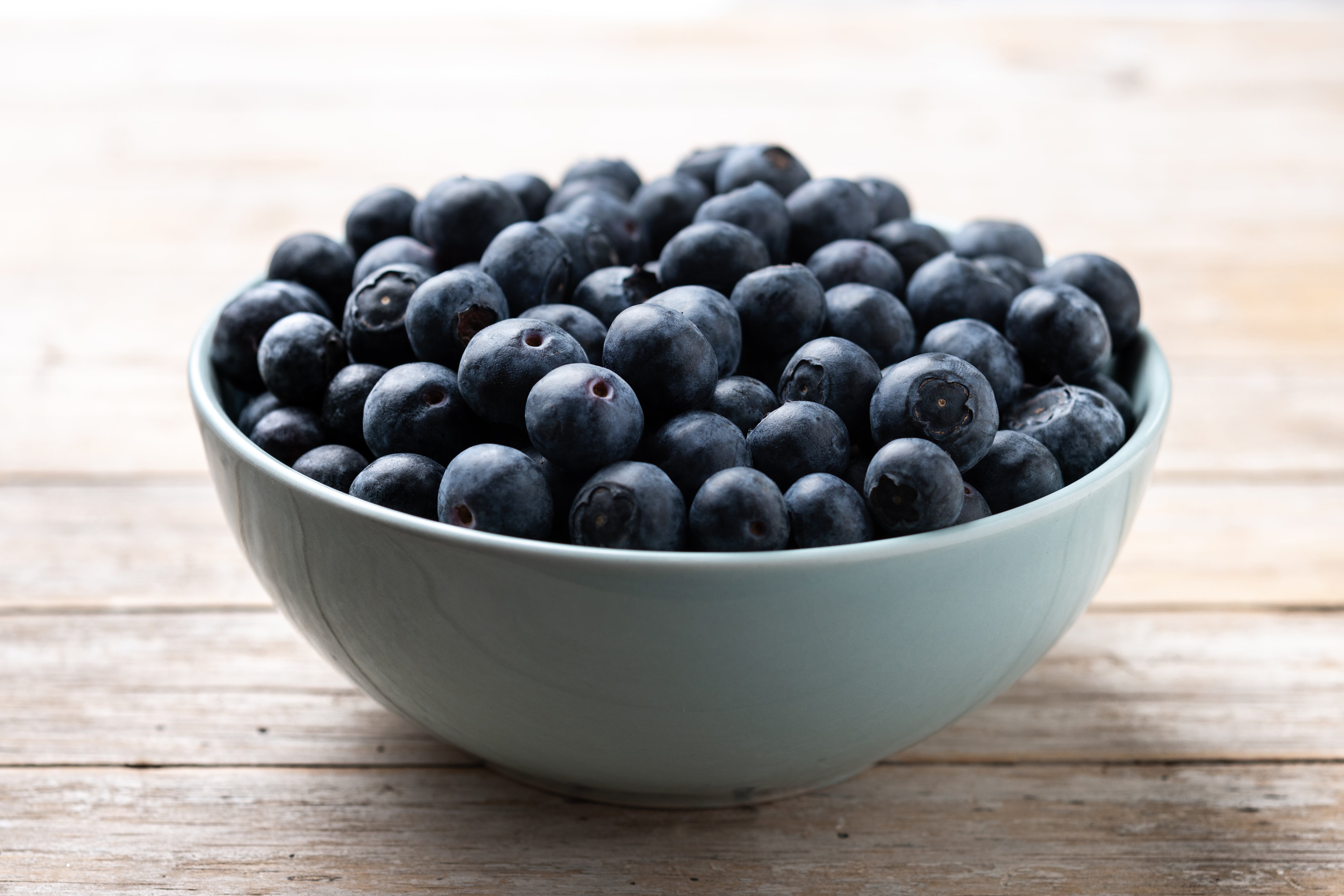 Bowl of blueberries on a wooden surface