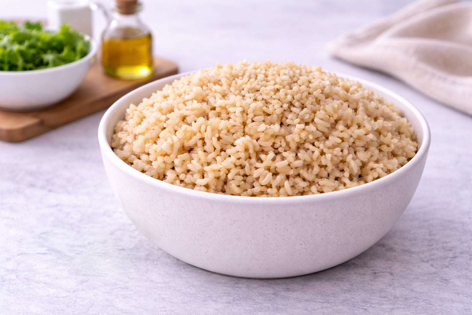 White bowl filled with cooked quinoa on a light gray surface.