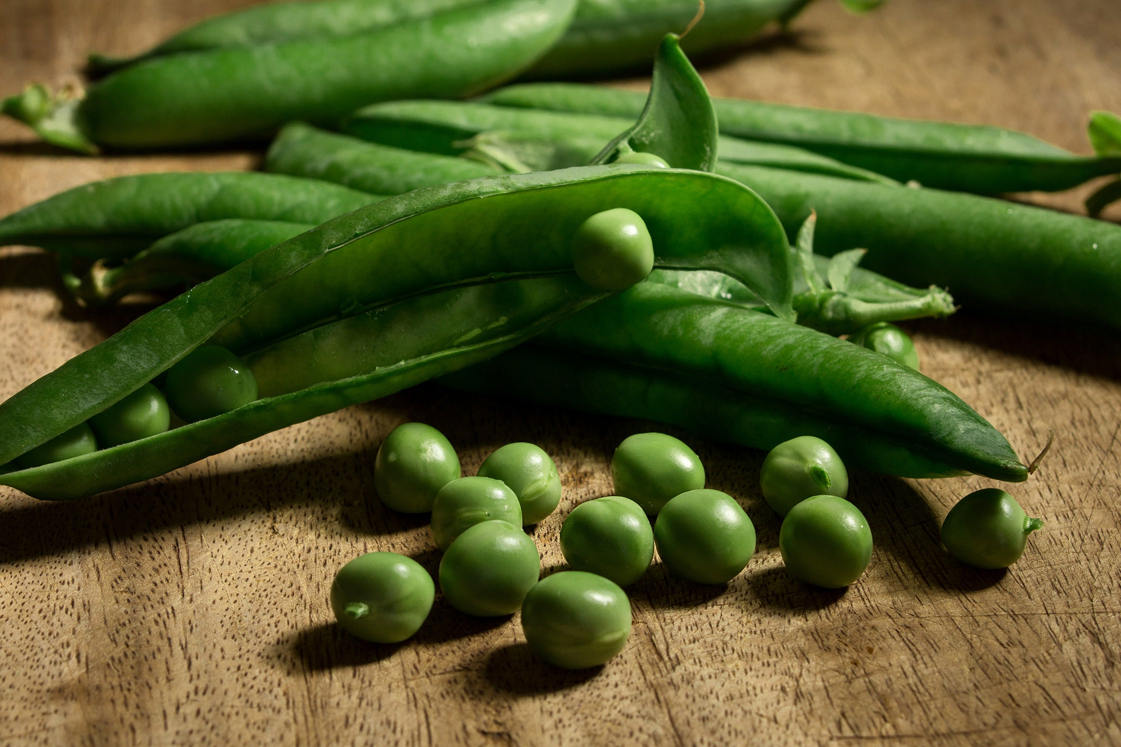 Green peas and pods on a wooden surface