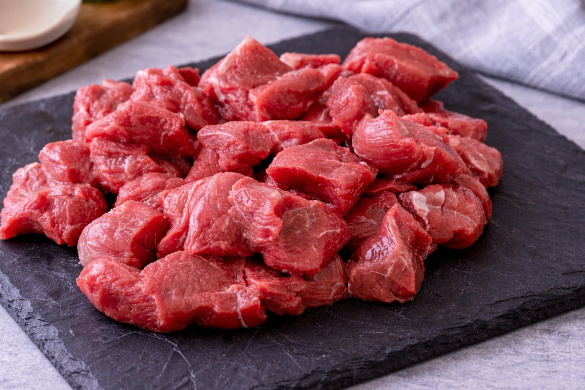 Raw beef chunks on a black slate surface